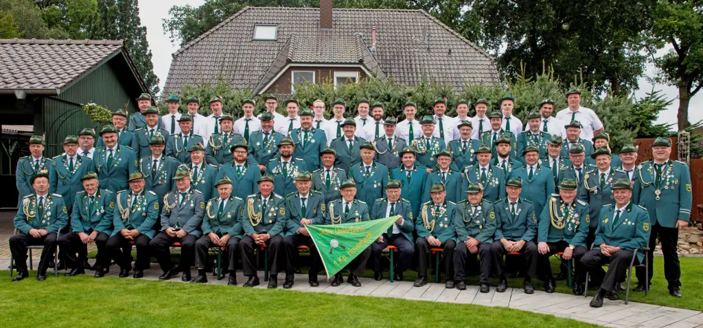 Gruppenfoto der I. Kompanie Haverbeck in Uniform vor einem Wohnhaus, in der Mitte die Kompaniefahne