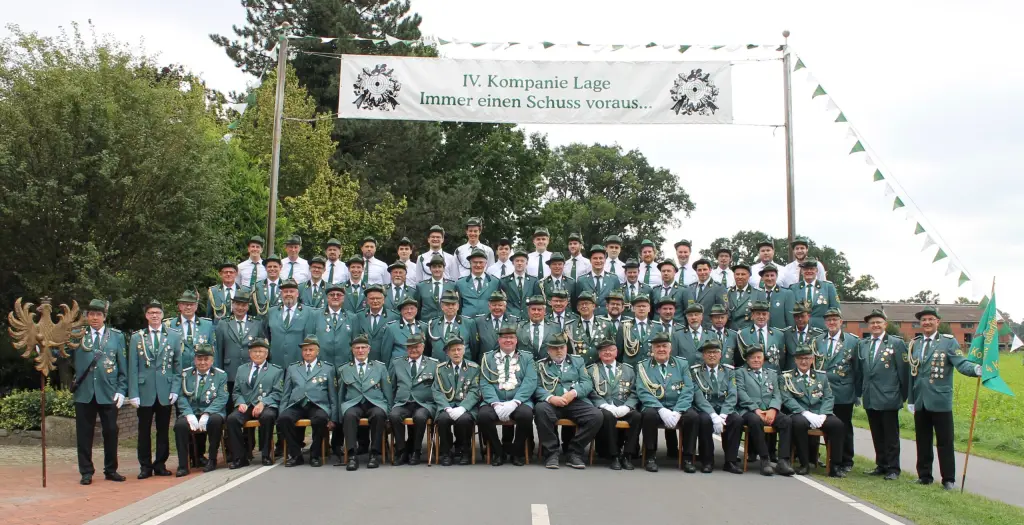 Gruppenfoto der IV. Kompanie Lage auf der Straße unter dem Banner „IV. Kompanie Lage – Immer einen Schuss voraus…“