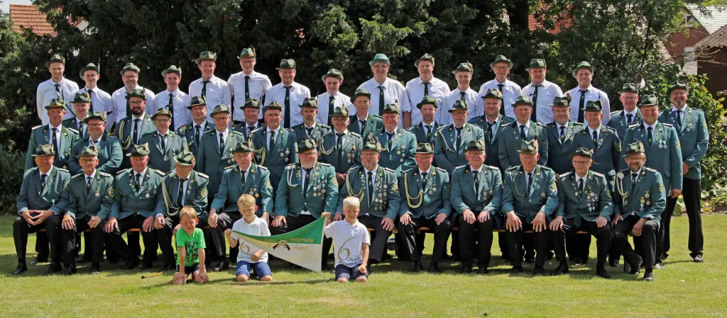 Gruppenfoto der VI. Kompanie Klünenberg im Garten, davor drei Kinder mit der Kompaniefahne